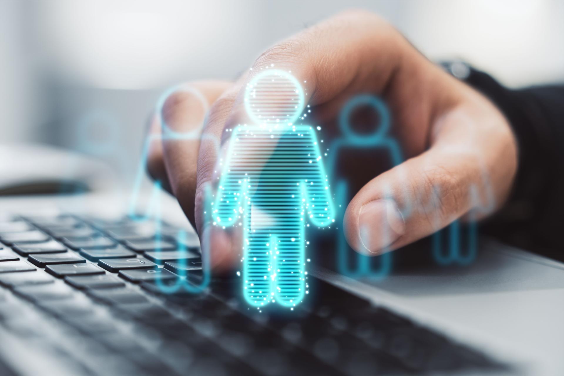 Hand selecting digital human icon on laptop keyboard.